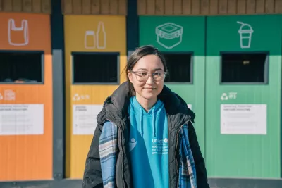 UNICEF Volunteer Altynai Segizbay standing near containers for recycled materials in Ecosen, Almaty, Kazakhstan.