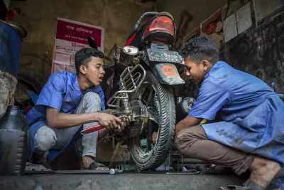Boys repair a motorcycle at a workshop in Bangladesh.