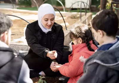 A dedicated youth mentor engages with children, sharing knowledge and fostering a love for nature in a hands-on learning environment.
