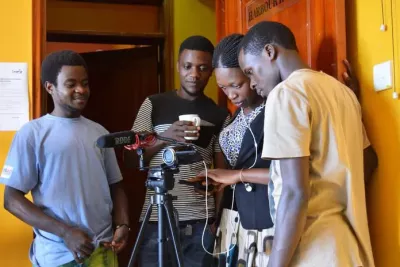 Four young people stand behind a camera as they learn skills in multimedia.