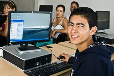 A young man uses a computer in Mexico, turning to face the camera.