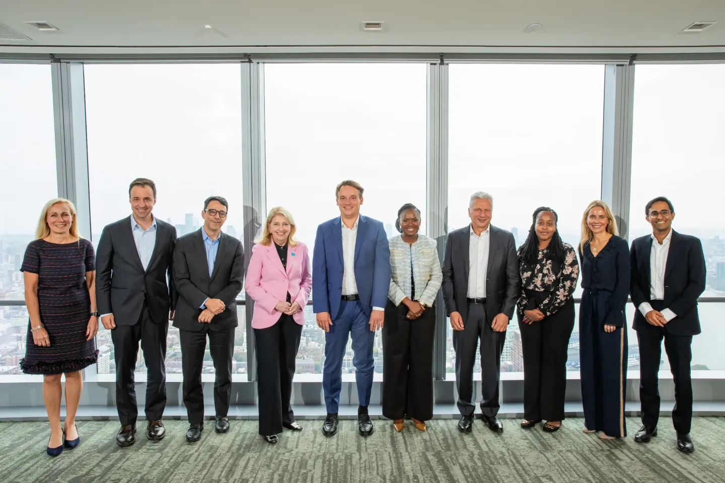 Generation Unlimited board members standing in a row in front of large floor‑to‑ceiling windows during a formal meeting