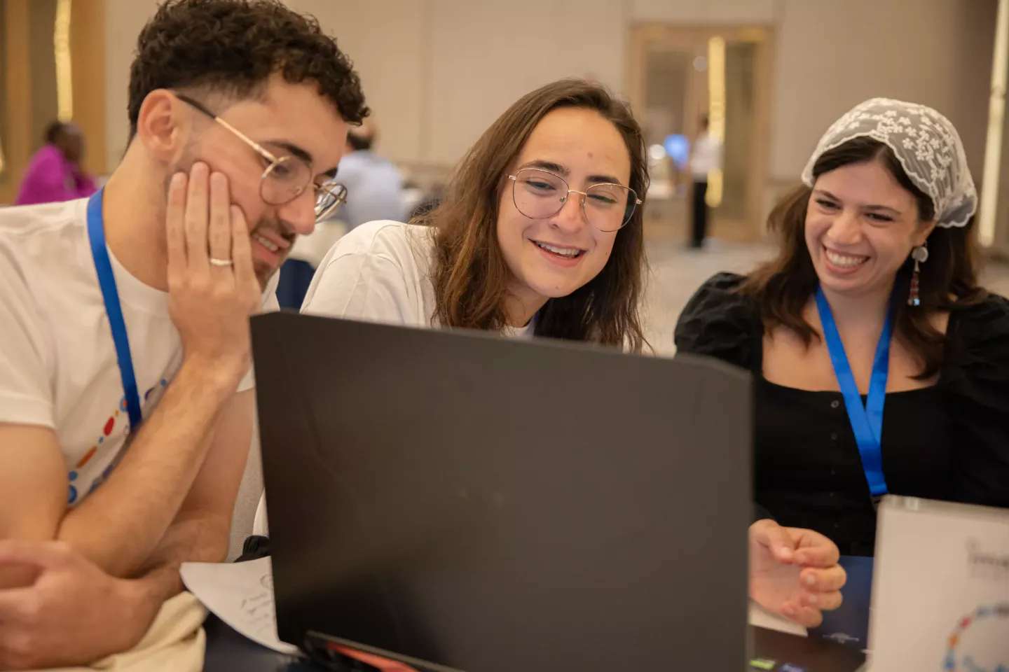 Three young people looking at the nootebook, working together and smiling 