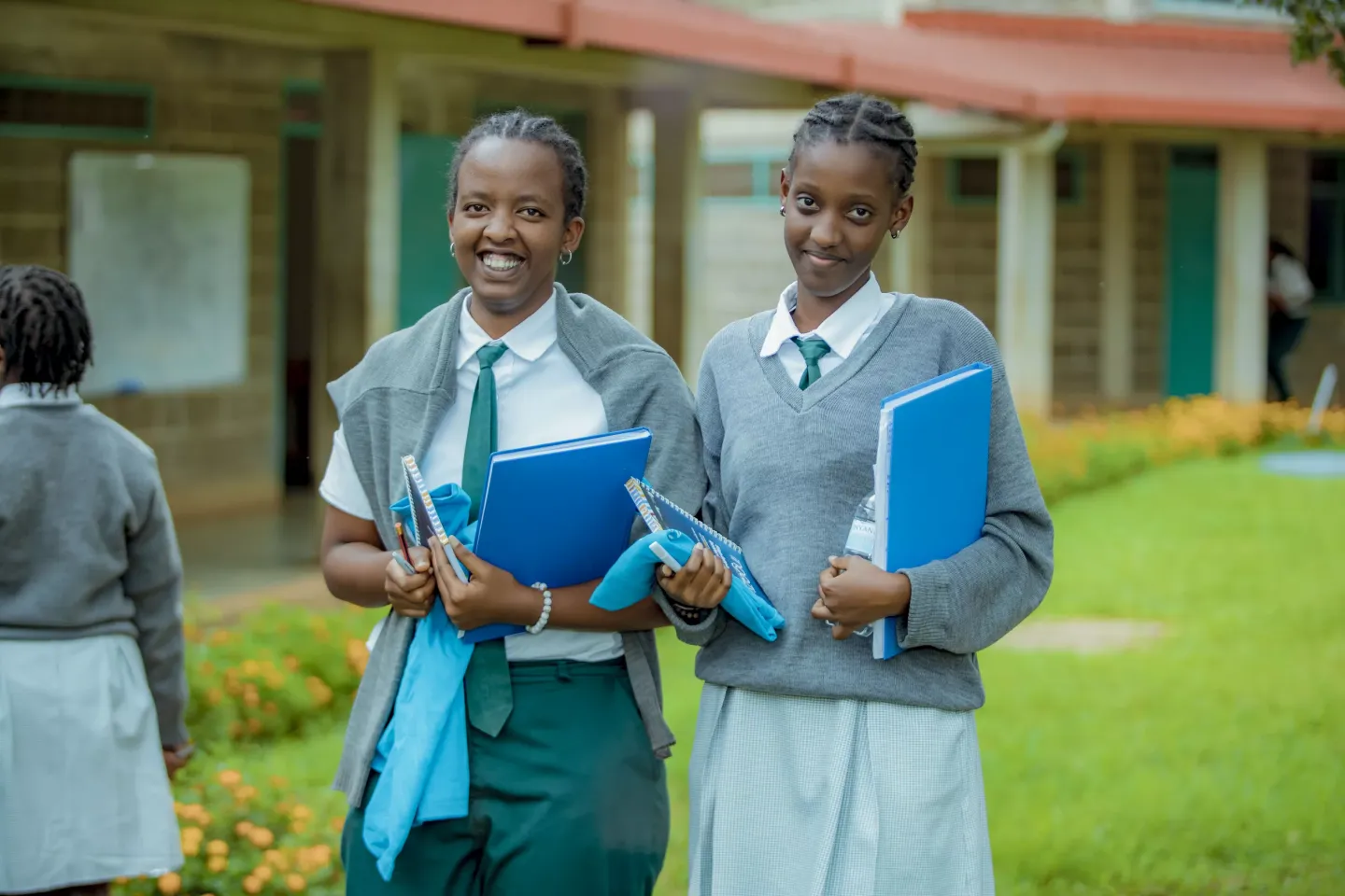 Two cheerful students in Rwanda enjoying a day at school, proudly holding their books and ready for a productive day of learning.