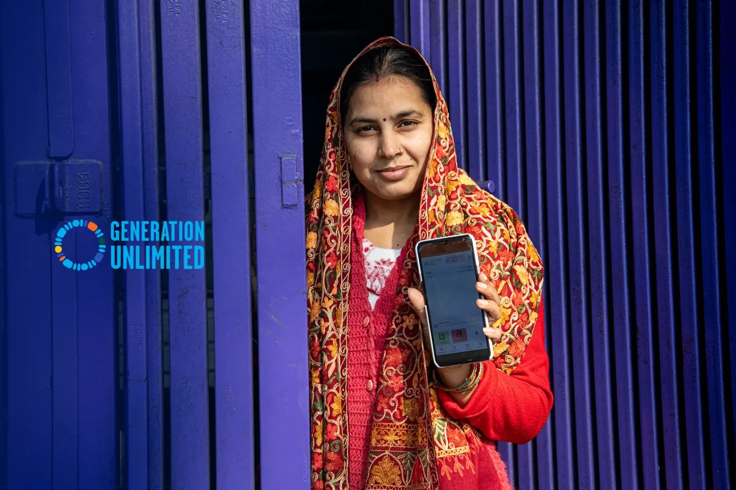 A young woman from India from the "Didi Ki Dukaan" initiative holding a smartphone upright