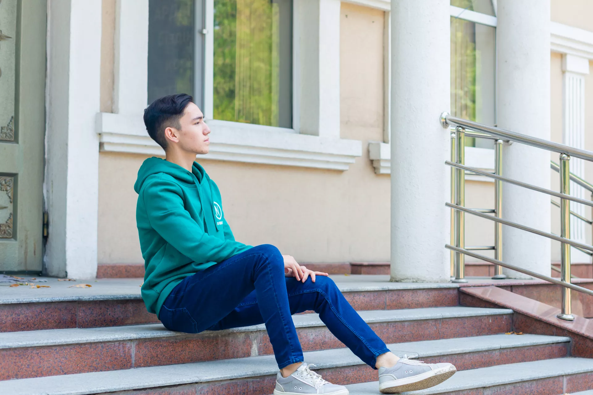 A young boy from Kazakhstan sitting on a stairway
