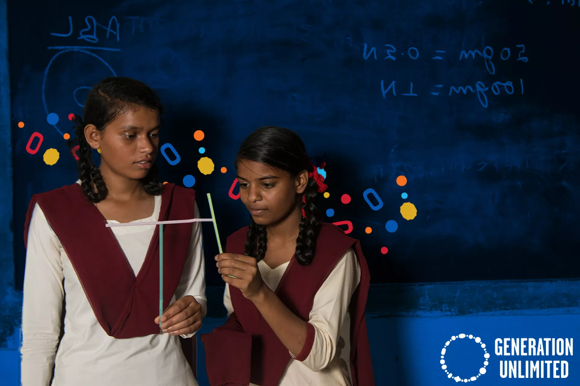 Two girls in front of a classroom blackboard