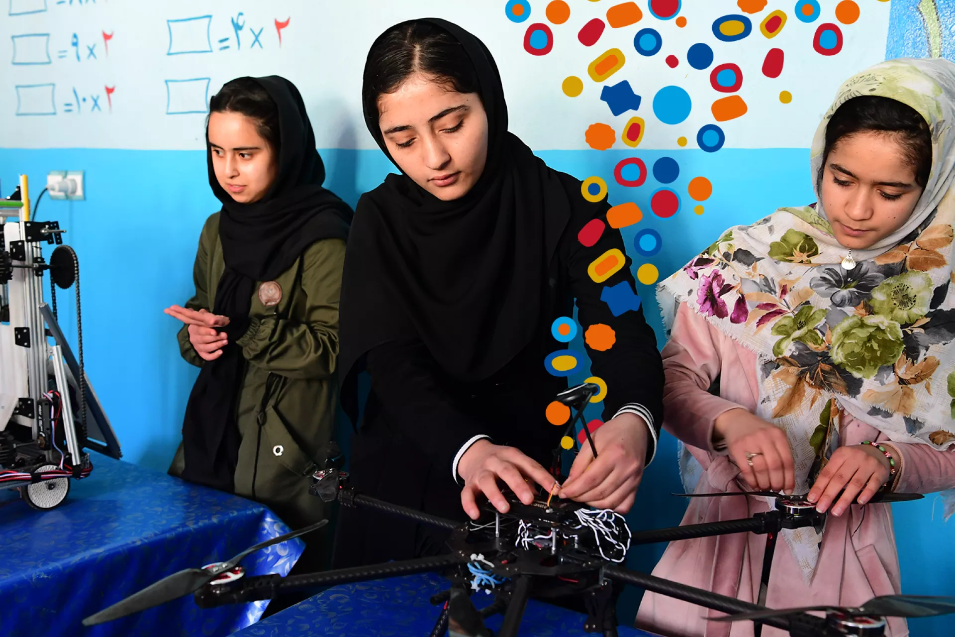 Young girls from Afghanistan who are trained in robotics are depicted tinkering with a drone, with GenU beads superimposed.