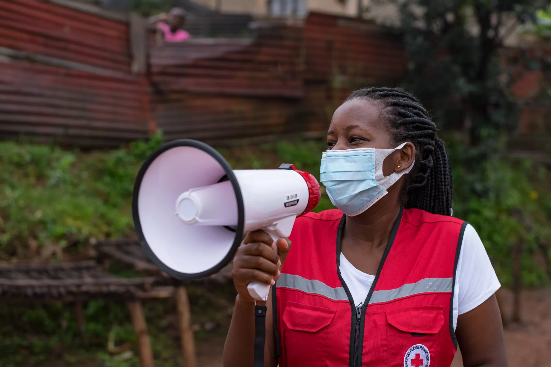 A volunteer with a red velvet Red Cross jacket is speaking on a megaphone