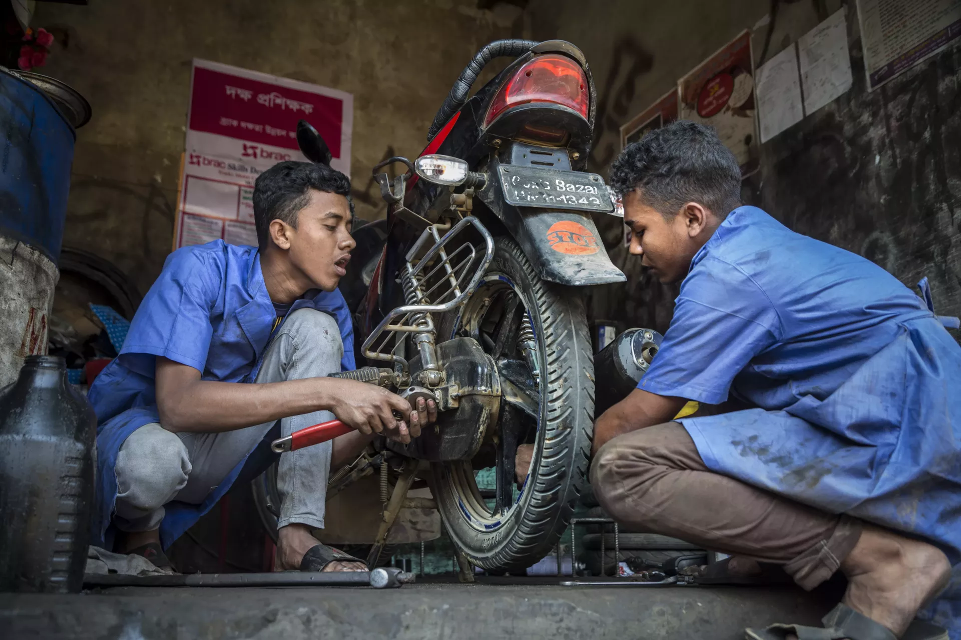 On 20 February 2019 in Bangladesh, (left-right) Mohammed Forhad and Biplob Barca, both 18 years old, work on a motorbike in a garage in Court Bazar, in the Cox's Bazar district.