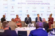 A panel of speakers seated onstage during the Generation Unlimited Global Leadership Council, with an audience watching and a backdrop displaying partner logos.