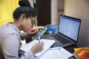Girl studying using her computer, notebook and a calculator