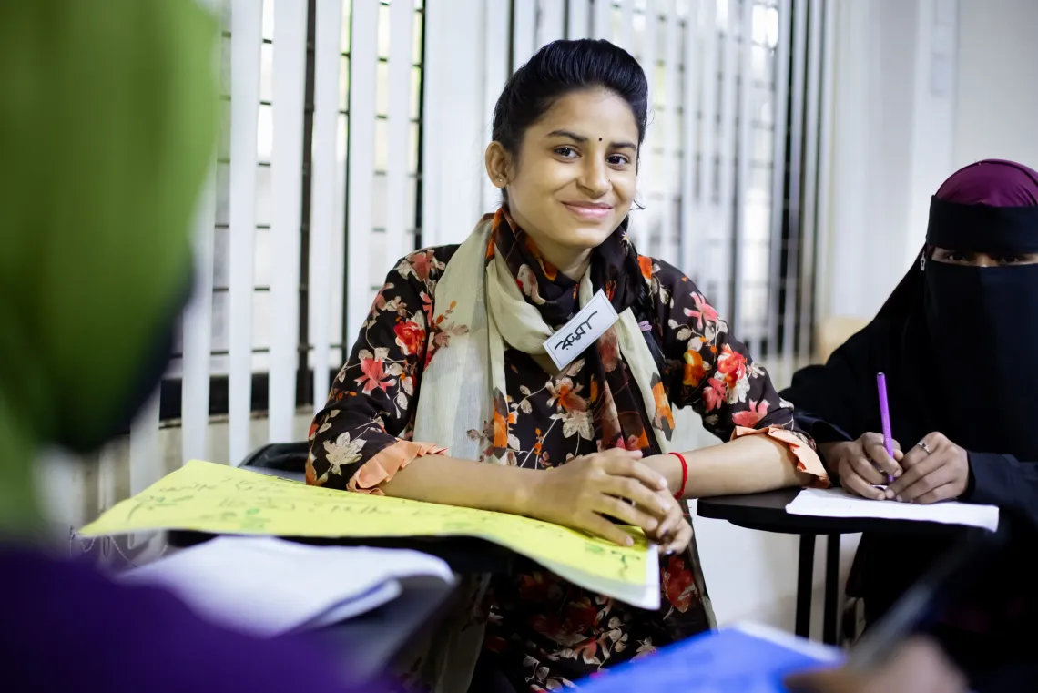 A young woman smiles while sitting at a desk during a GESP skills training session in Bangladesh.