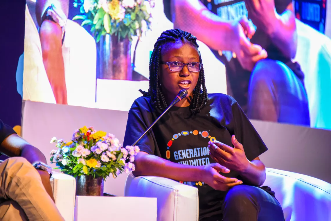 A young Nigerian girl on stage speaking into a microphone during a panel discussion