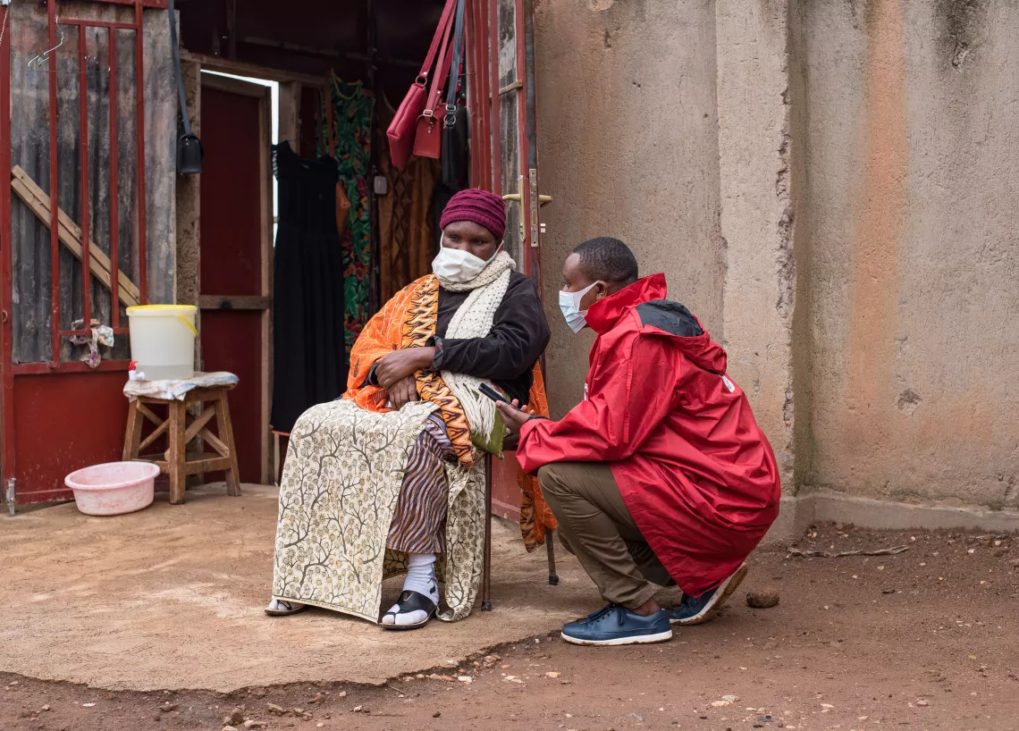 Faustin, a data collector from Red Cross carries out a questionnaire with Virginie, a store owner in Kimironko, to record how much she knows about COVID-19.