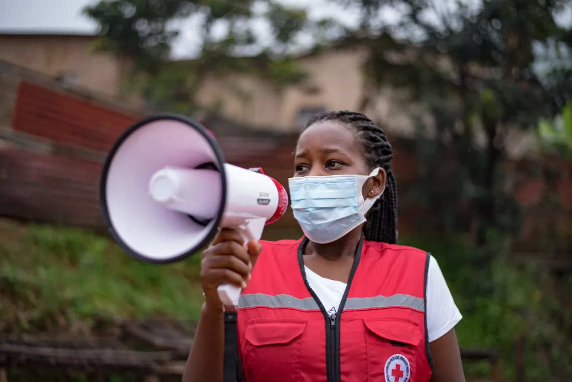 Justine, a Red Cross volunteer, informs people in the Gatsata community through her megaphone on how to effectively practice COVID measure.