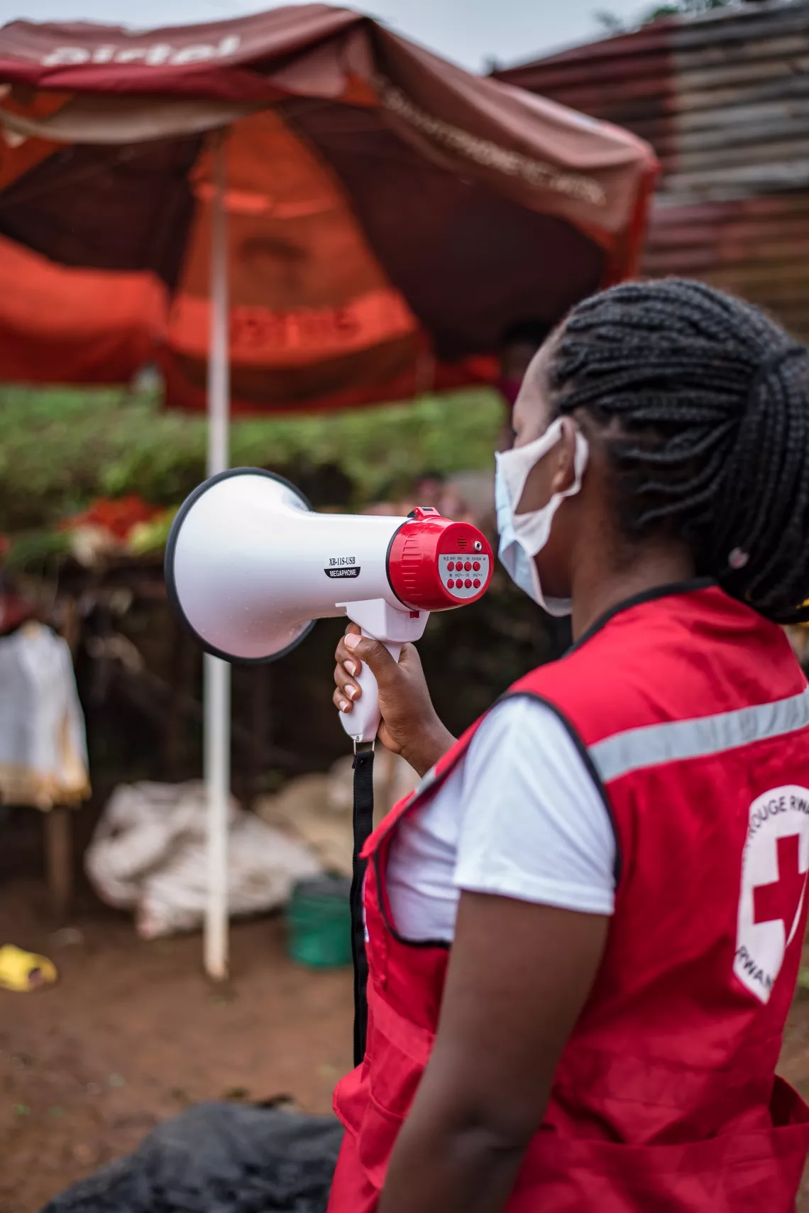 Justine, a Red Cross volunteer, informs people in the Gatsata community through her megaphone on how to effectively practice COVID measure.