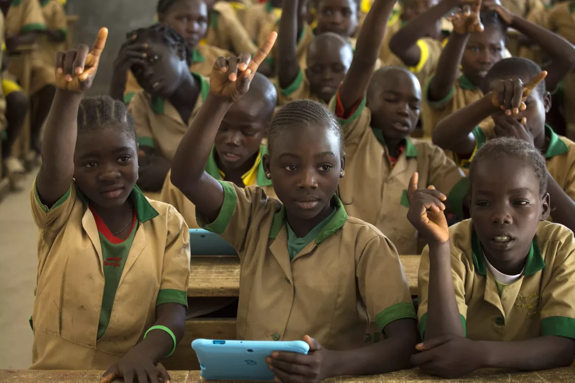 Twelve-year-old Waibai Buka (centre), holding a computer tablet provided by UNICEF, raises her hand to answer a question at a school in Bagai, northern Cameroon, Tuesday 31 October 2017.