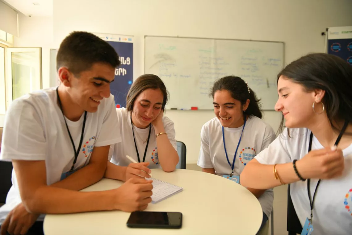 Four young people discuss idea around a table at bootcamp in Armenia