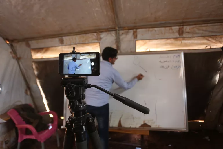 Walid Al-Daghim, a volunteer teacher at the Kili IDP camp in rural Idlib, records an Arabic language lesson on his mobile phone to be sent later to his students through a WhatsApp group.