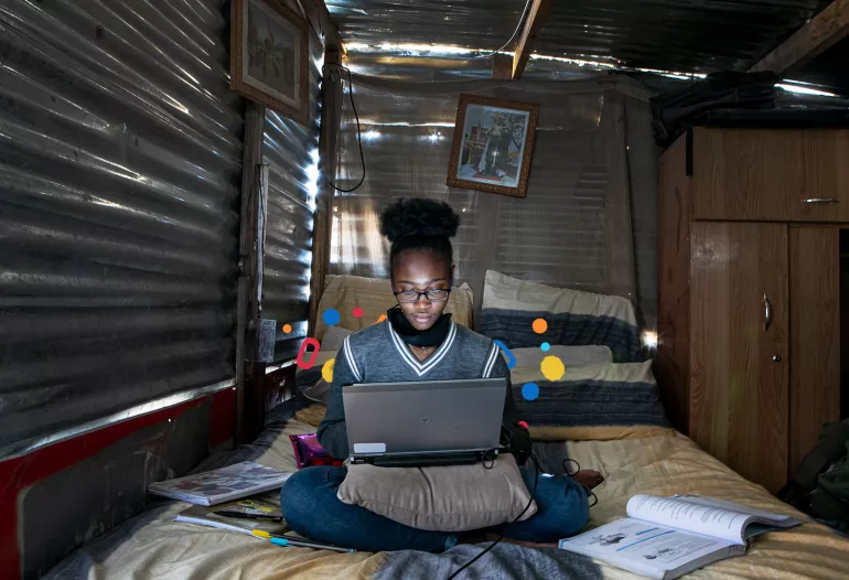 A young girl sitting on her bed in front of her laptop