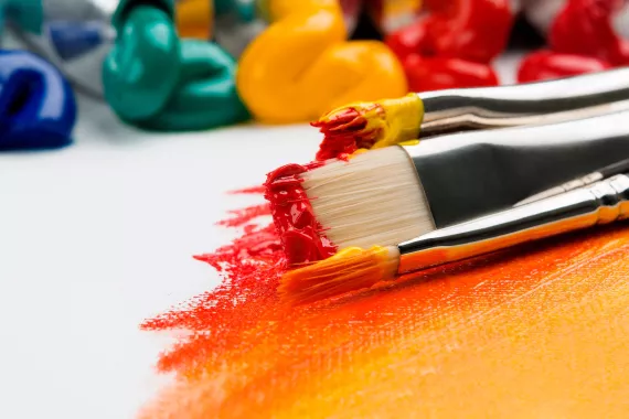 A close-up photo of paint brushes and paint on a canvas..