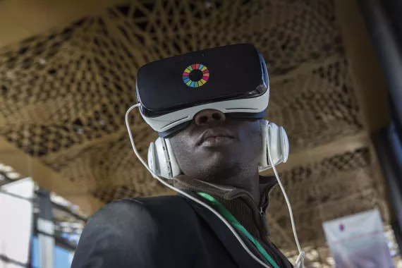 Journalist Babacar Fall, wearing a headset, watches a virtual reality video at the UNICEF exhibition at the Global Partnership for Education (GPE) Financing Conference in Diamniadio, Senegal